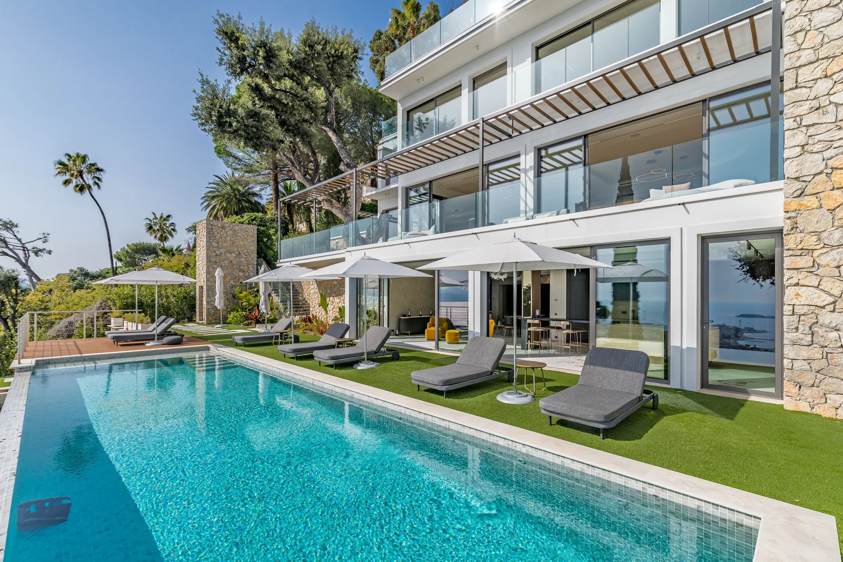 Piscine longue avec transats face à la façade contemporaine