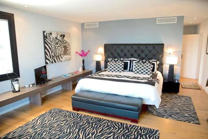 Chambre double avec tete de lit capitonnee grise, deco zebre noir et blanc et acces terrasse