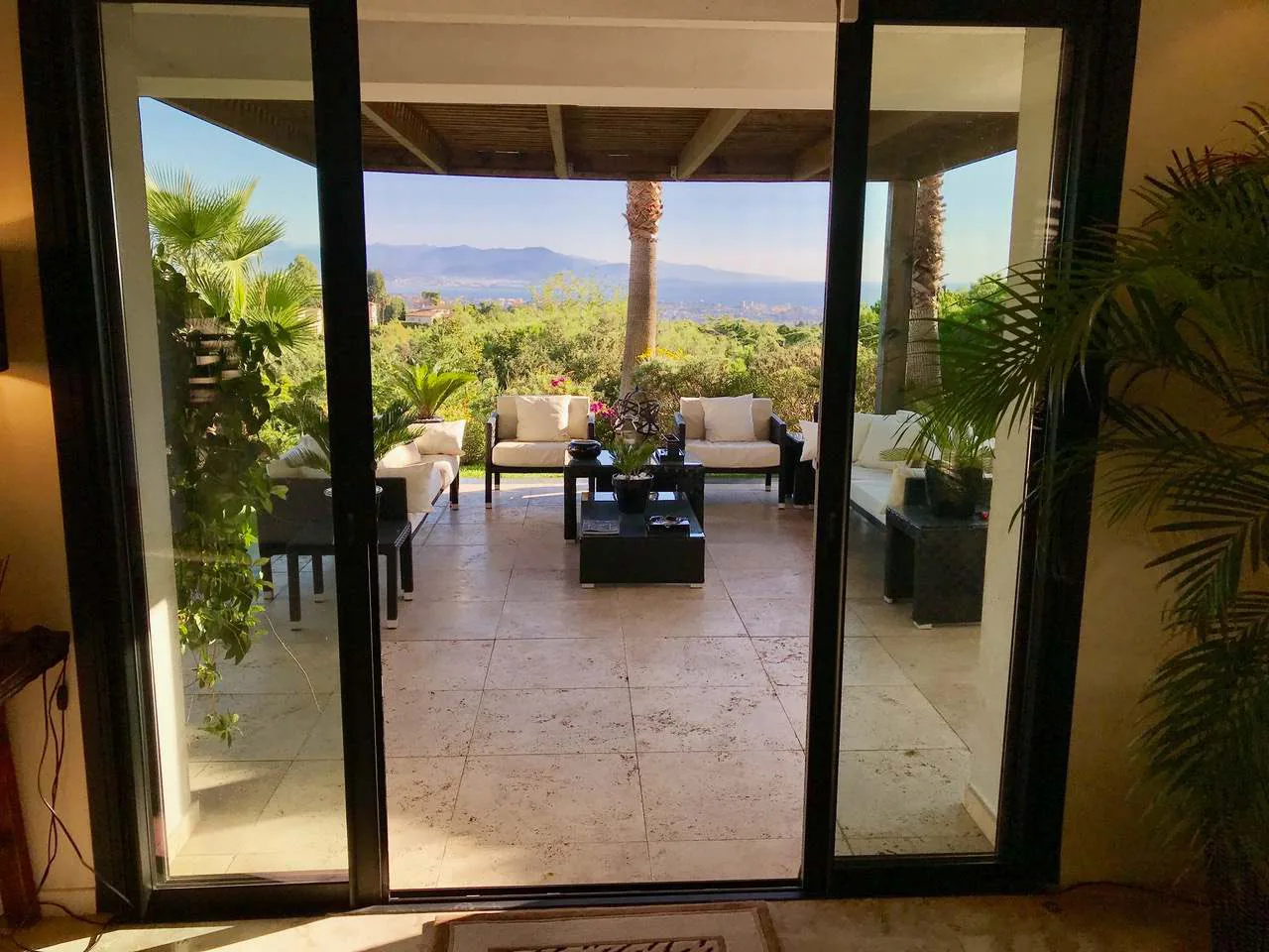 Vue depuis le salon vers la terrasse couverte et la baie de Cannes a travers les baies vitrees