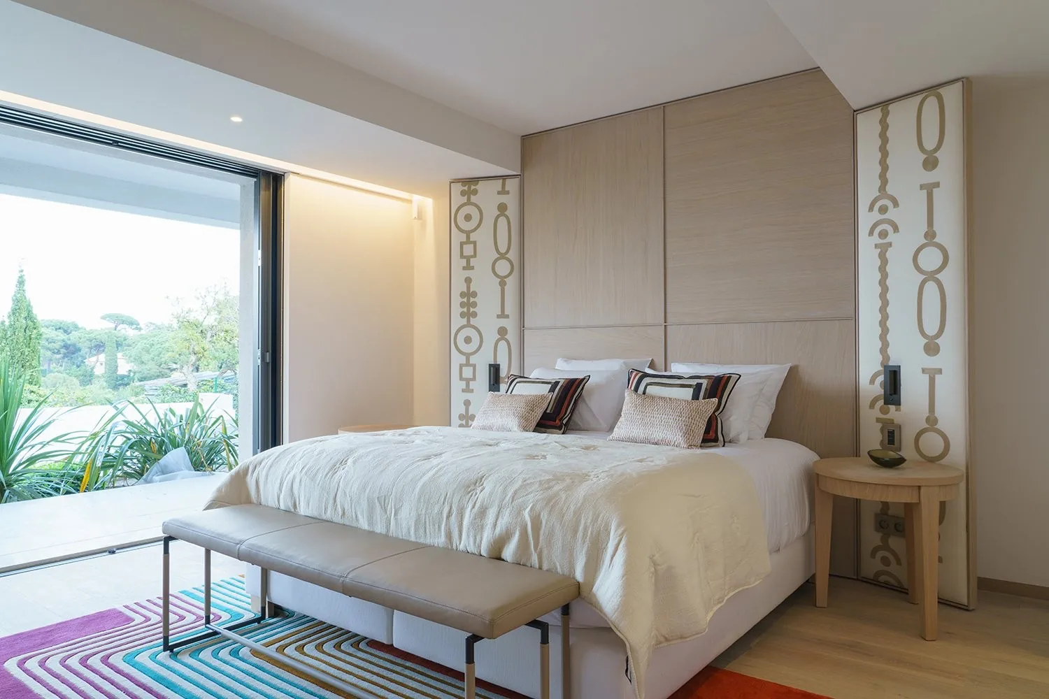 Chambre avec tete de lit motifs Hermes et tapis multicolore