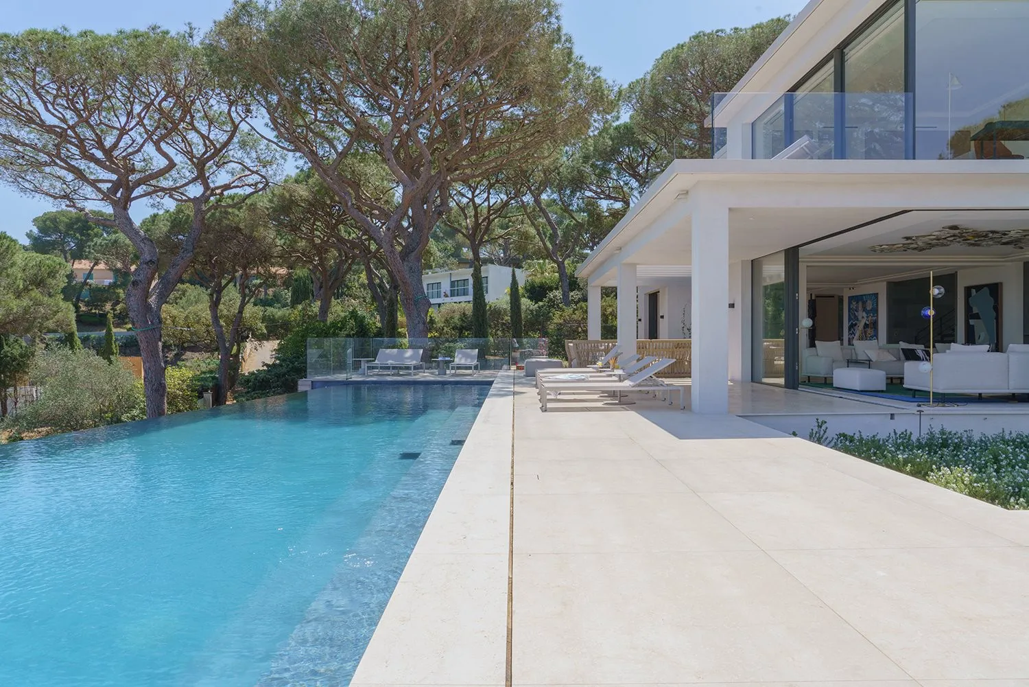 Piscine a debordement et deck en pierre claire face a la mer