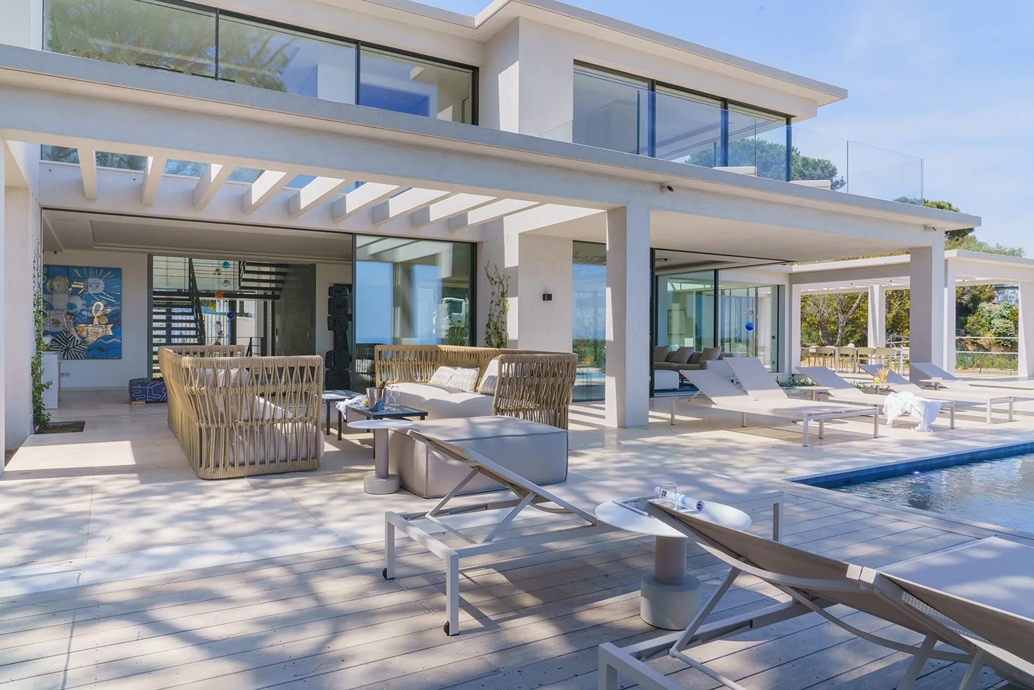 Terrasse couverte sous pergola, salons et bord de piscine