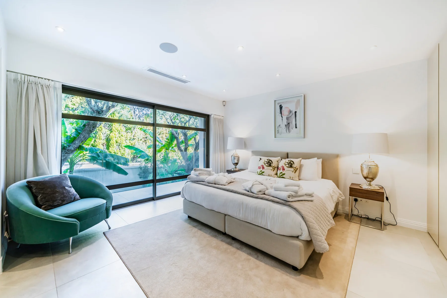 Chambre queen size avec linge ivoire et grande baie sur jardin tropical
