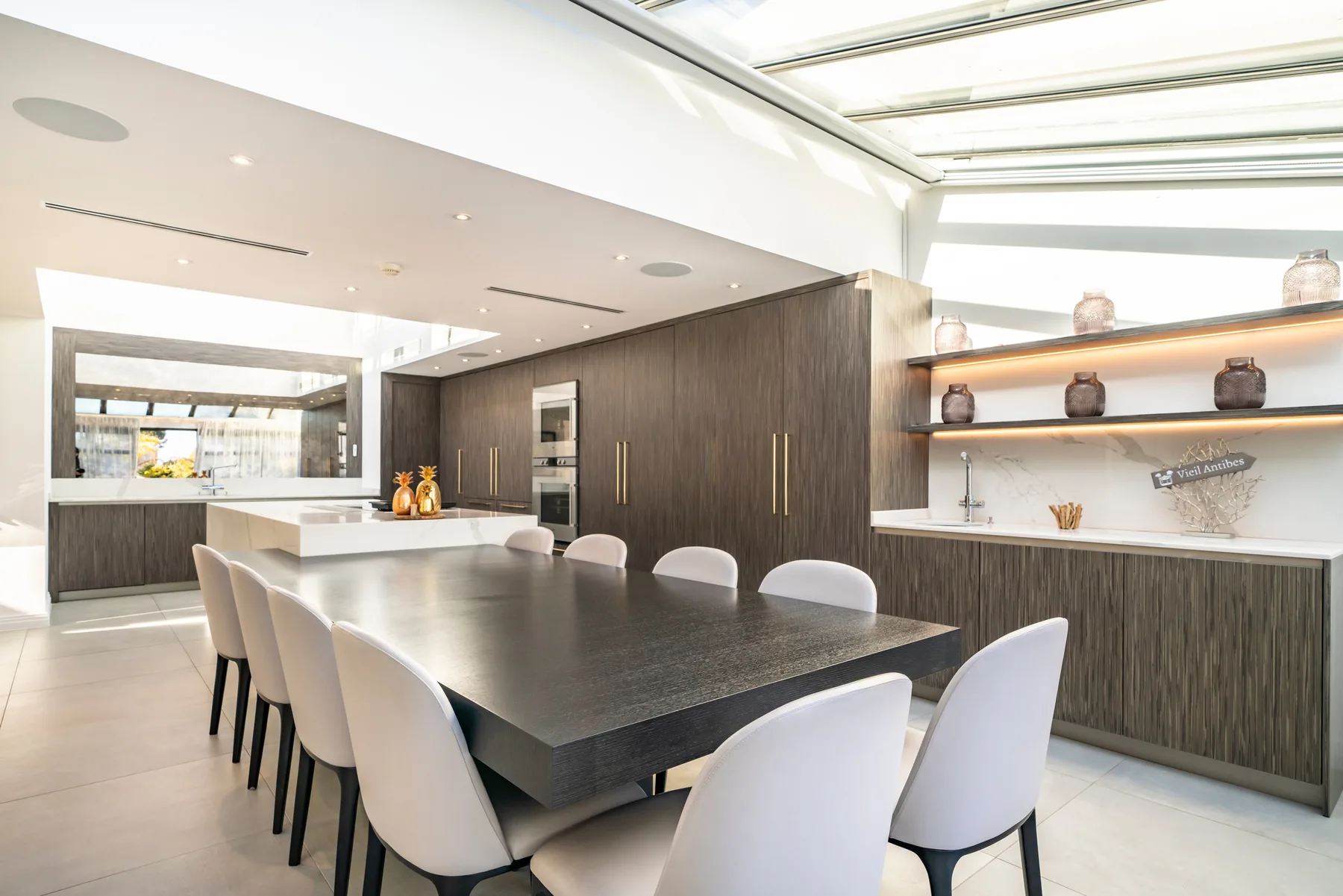 Salle à manger principale avec grande table en chêne et suspensions chromées