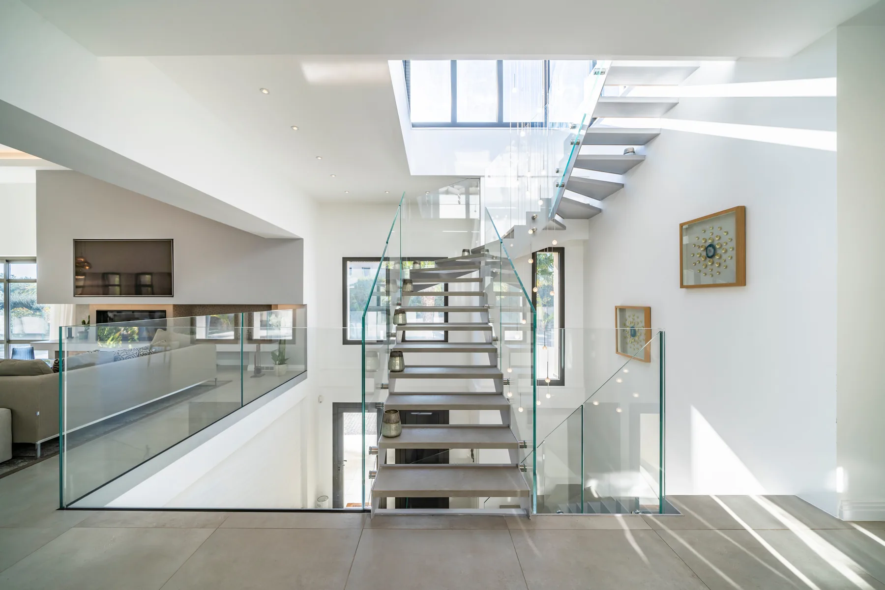 Hall d'entrée double hauteur avec escalier verre et console miroir