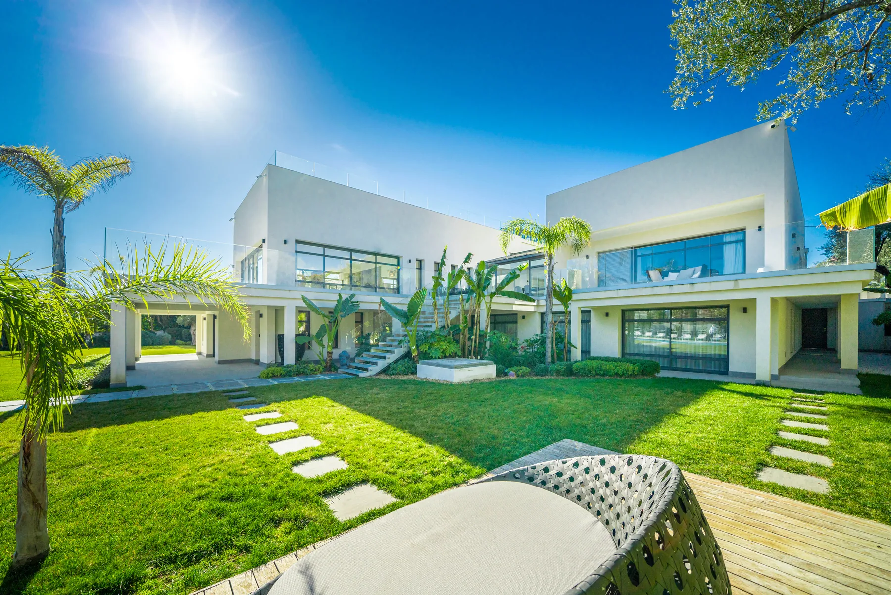 Arrière de la villa avec pelouse, allées pavées et façades blanches