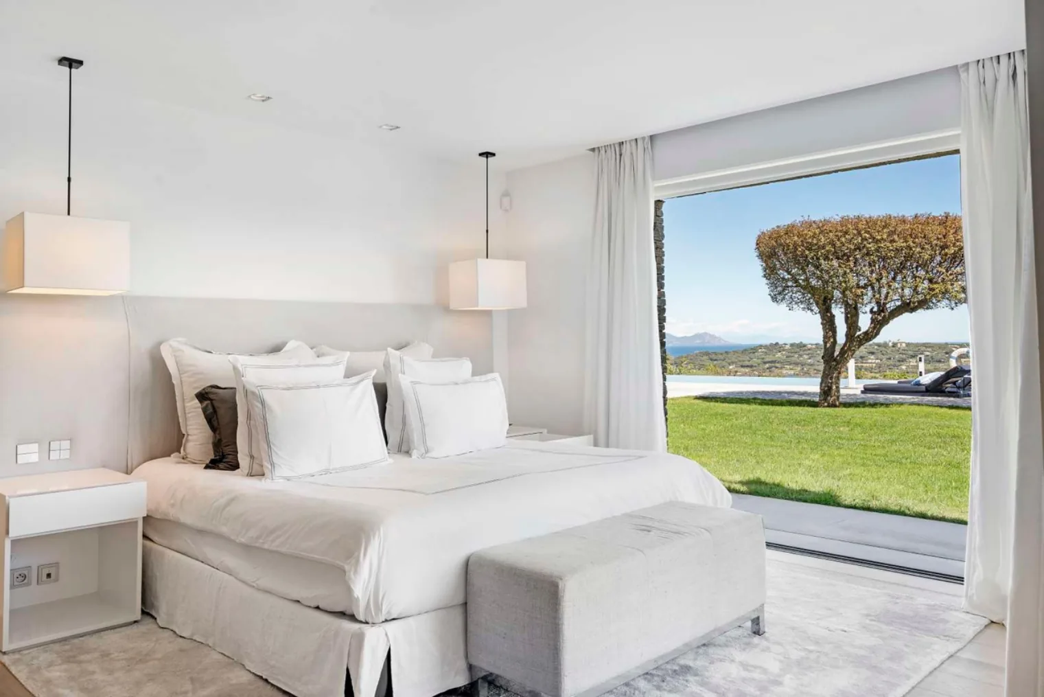 Chambre blanche vue mer avec arbre sculpte