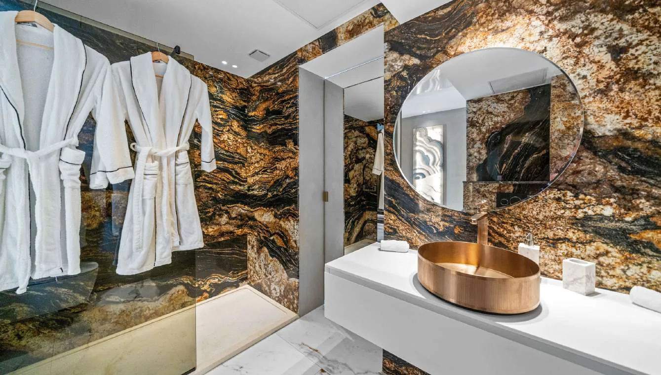 Salle de bain marbre or et noir avec double peignoir et miroir rond
