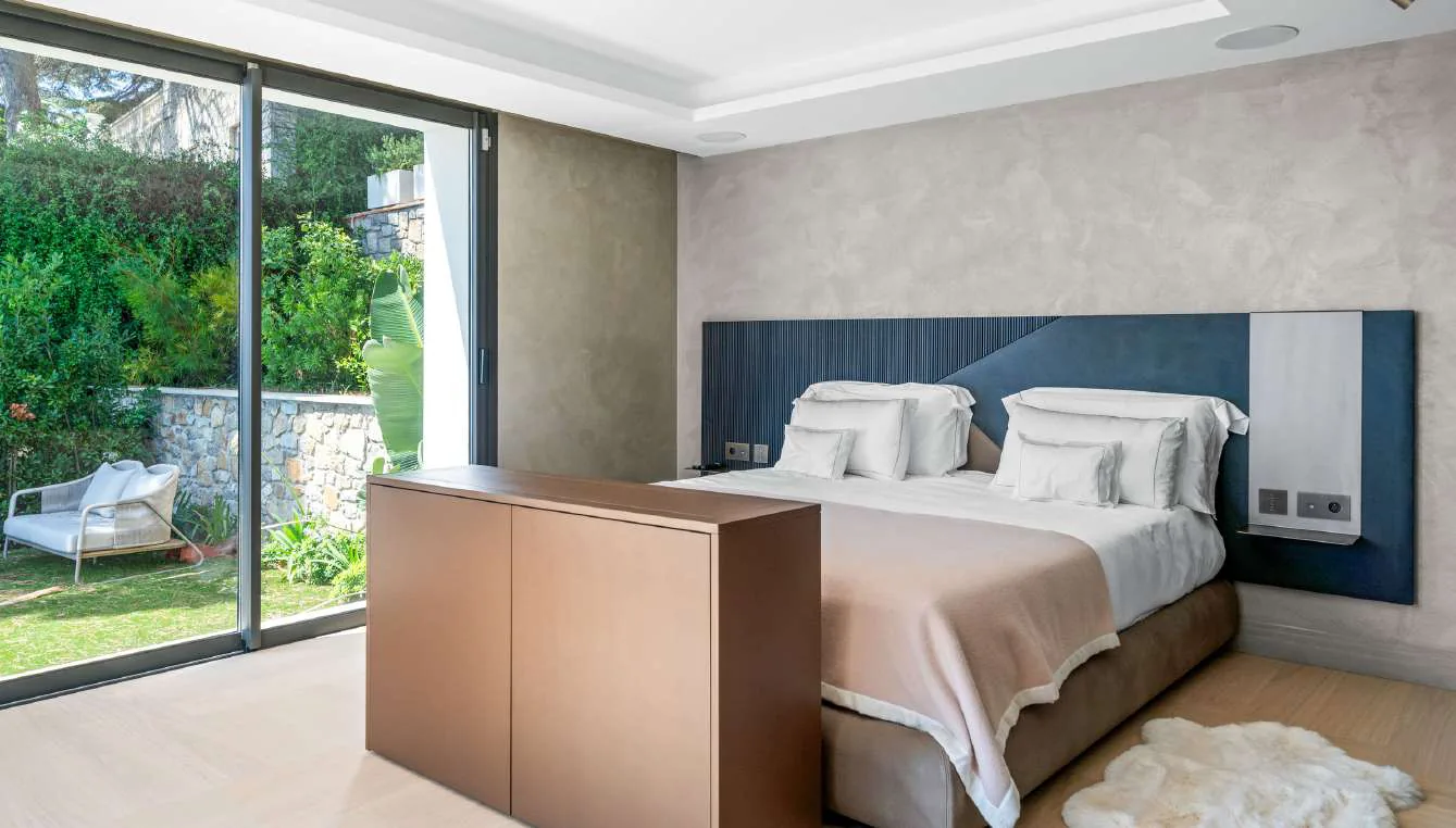 Chambre avec tête de lit bleu nuit côtelée et linge rose, vue jardin