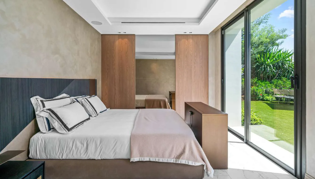 Chambre invités avec lit double, panneaux bois clair et accès jardin