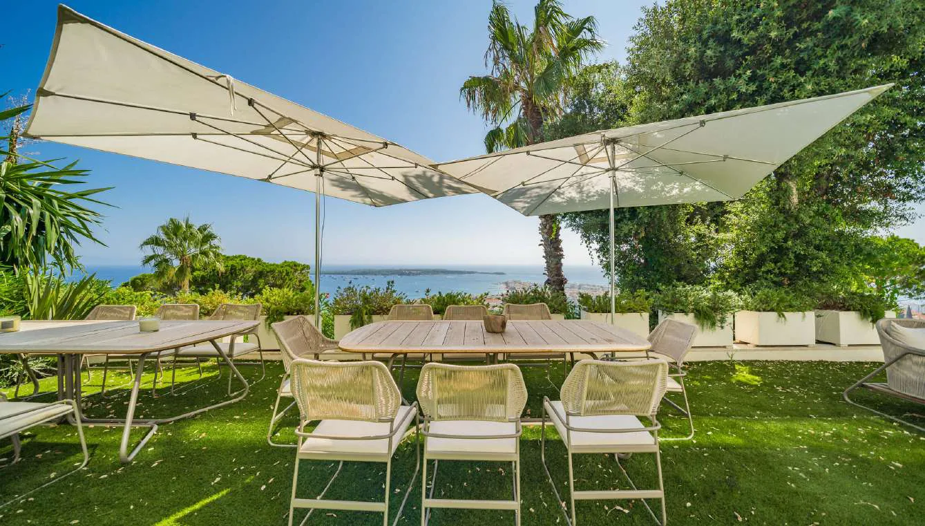 Salle à manger extérieure couverte avec table bois et vue sur la baie