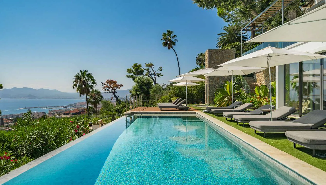 Piscine, palmiers et parasols face à la baie de Cannes