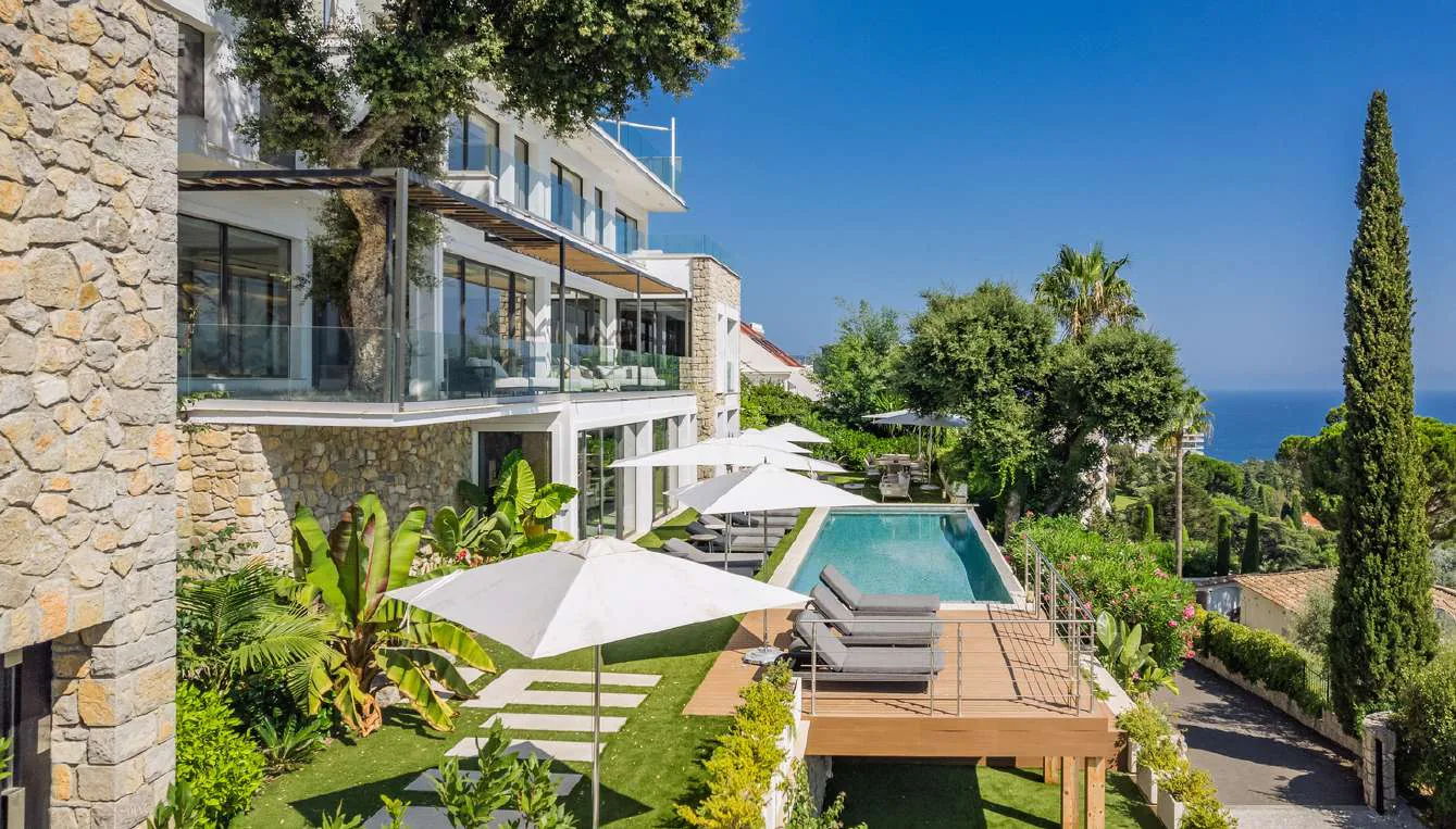 Piscine côté jardin paysagé avec cyprès et vue mer