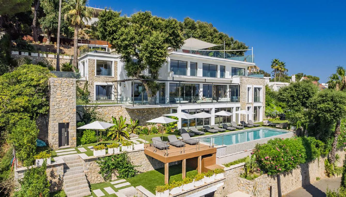 Piscine face à la villa, parasols et baies vitrées coulissantes
