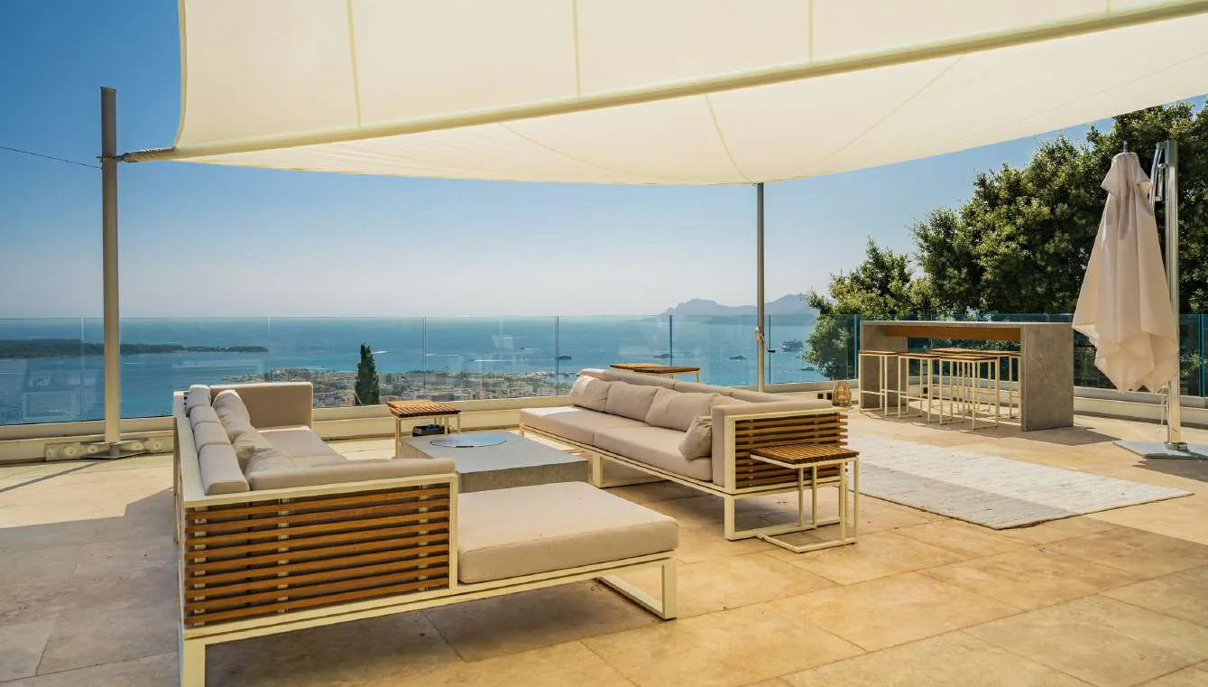 Salon rooftop sous voile d''ombrage avec vue baie panoramique et îles de Lérins