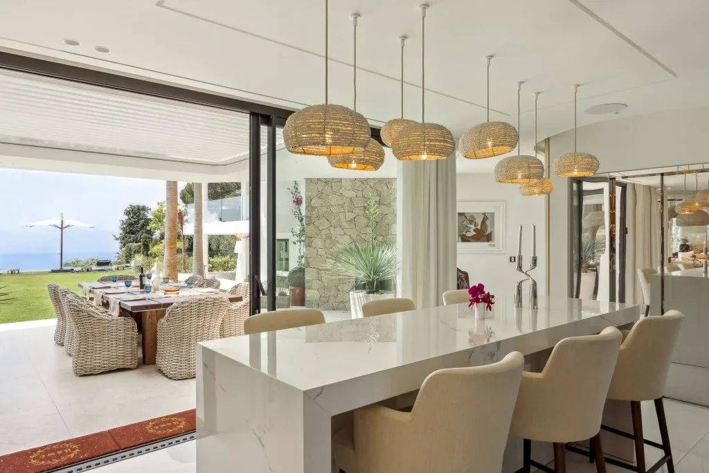 Salle à manger avec suspensions rotin tressées et vue jardin