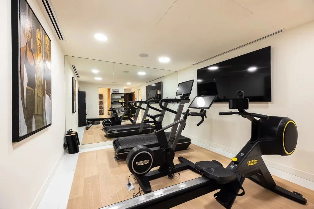 Salle de sport équipée Technogym avec tapis, rameur et écran connecté