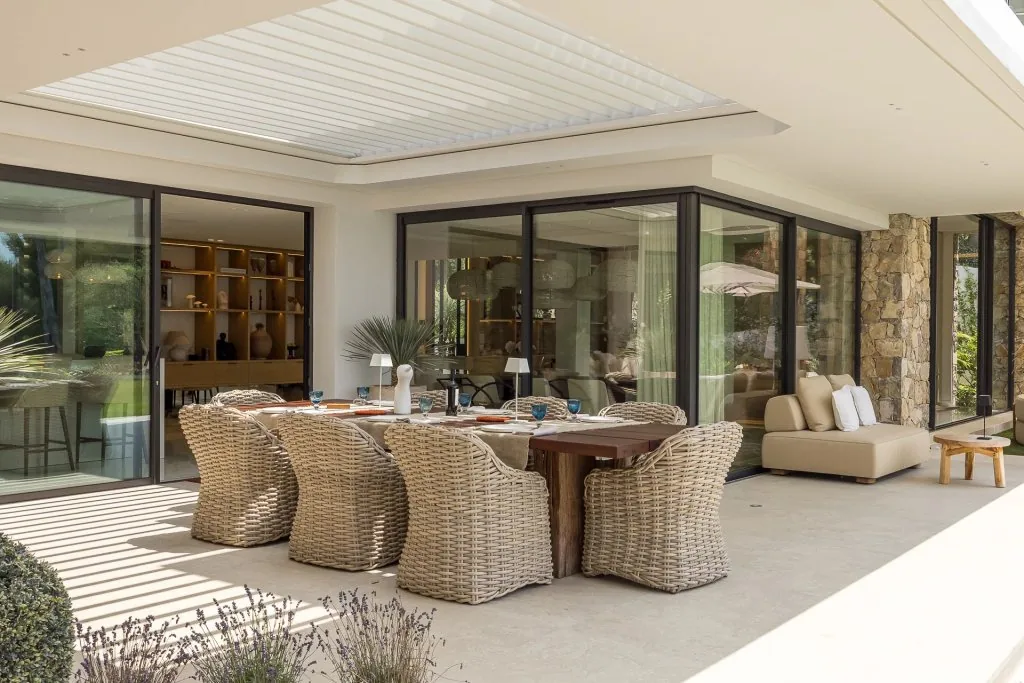 Salle à manger extérieure couverte avec mobilier rotin et vue jardin