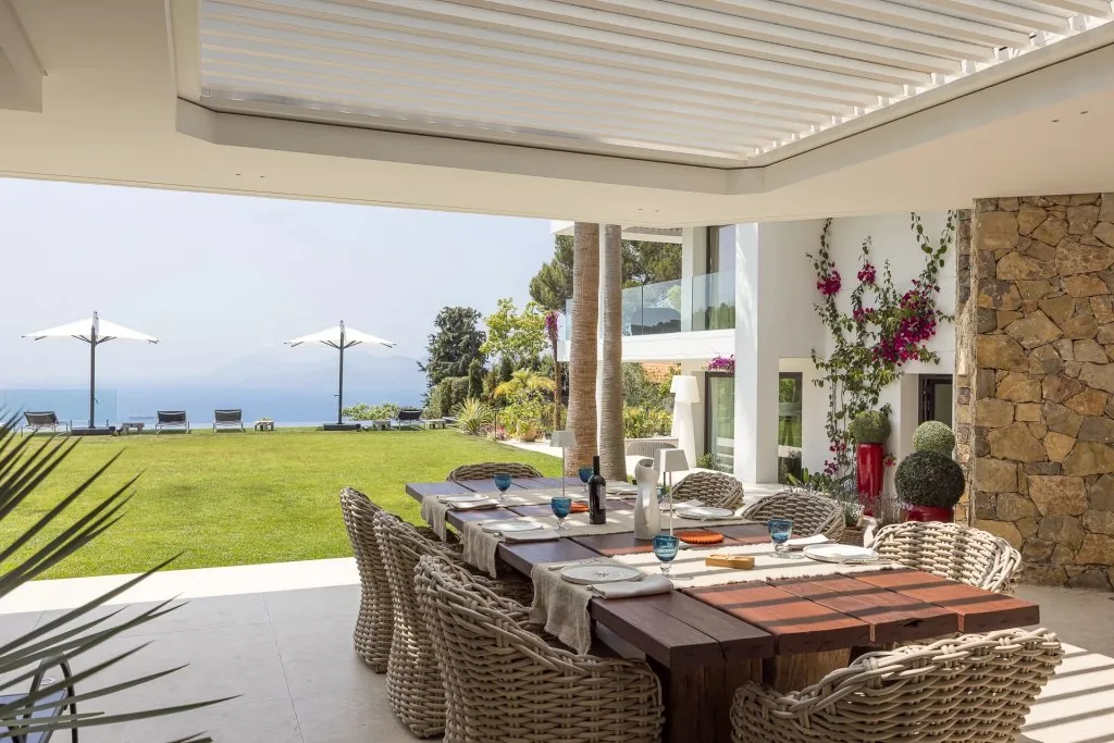 Salle à manger extérieure sous pergola bioclimatique avec vue mer