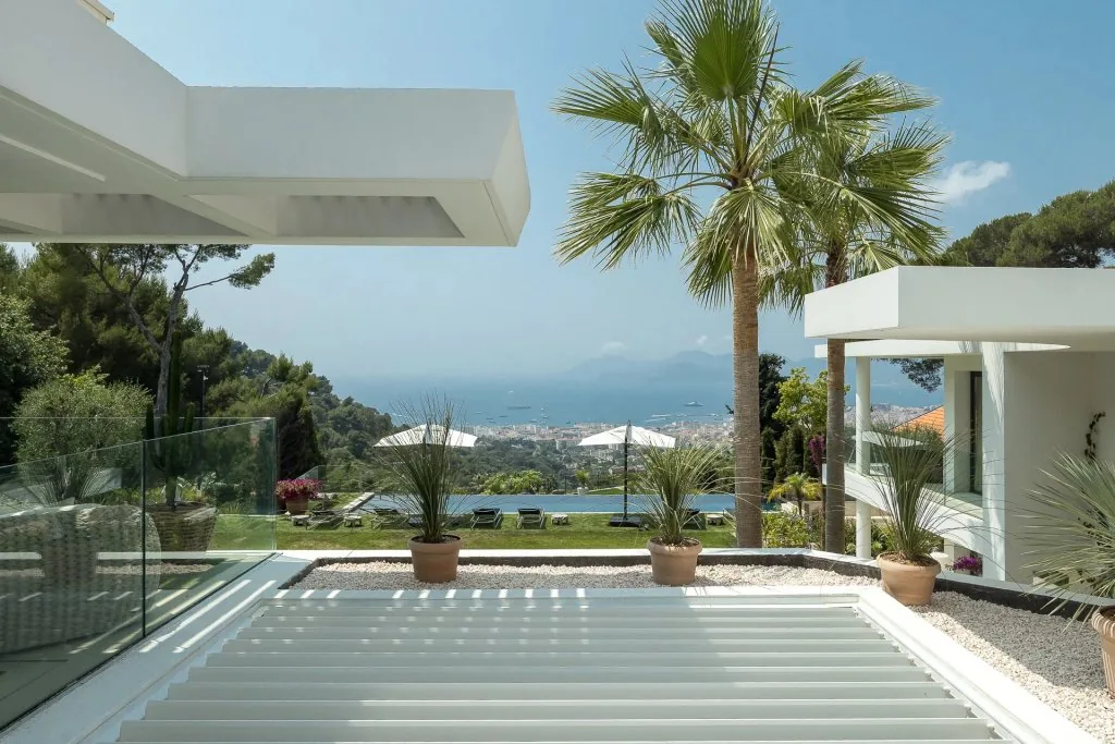 Piscine à débordement, palmiers et façade de la villa côté jardin