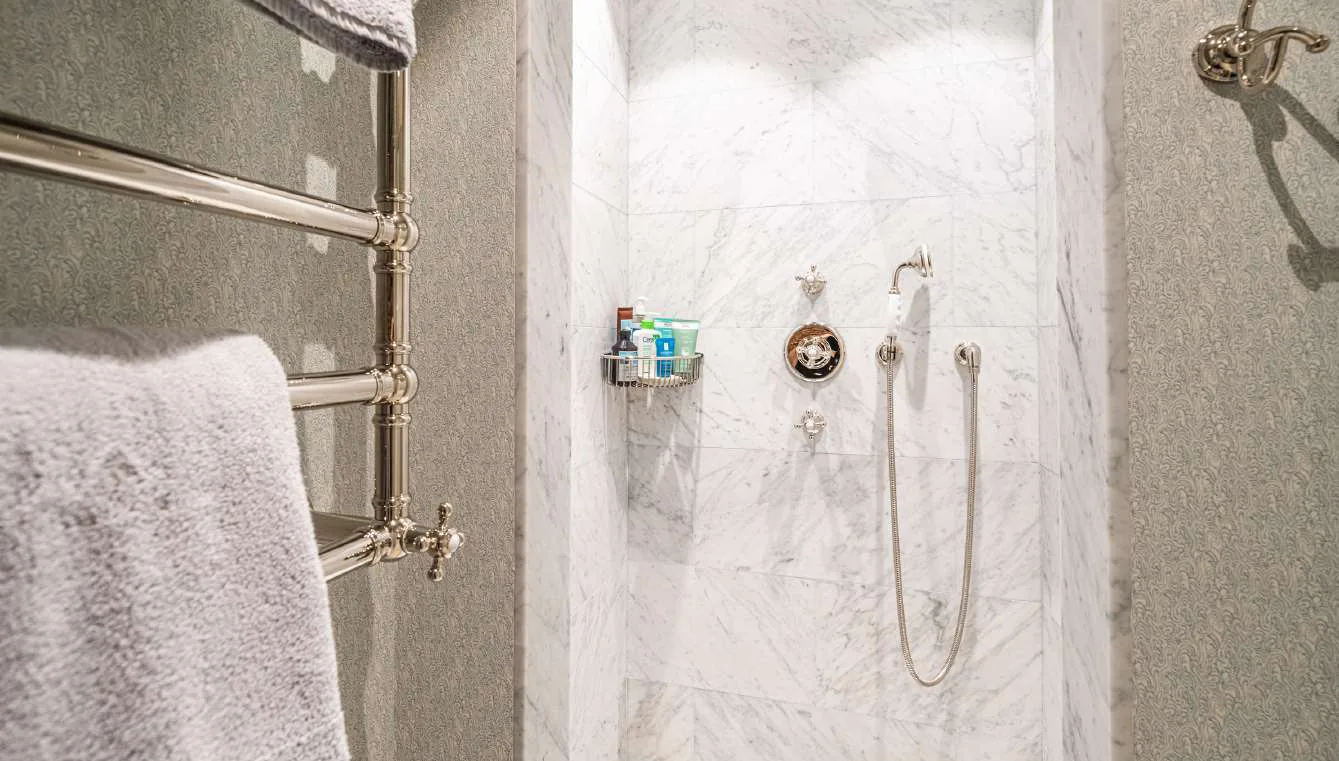 Salle de bain en marbre avec douche italienne walk-in et tapis raye