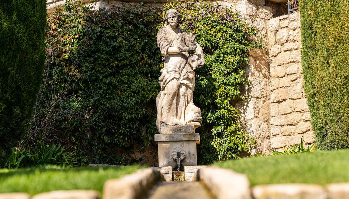 Cour pavee de galets avec fontaine centrale et cypres
