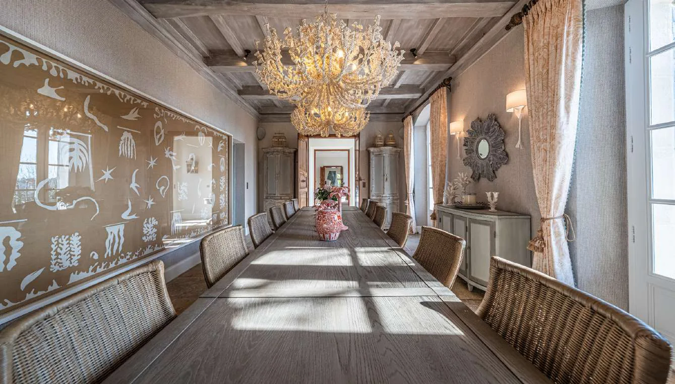 Grande salle a manger avec lustre cristal, fresque murale et chaises en rotin