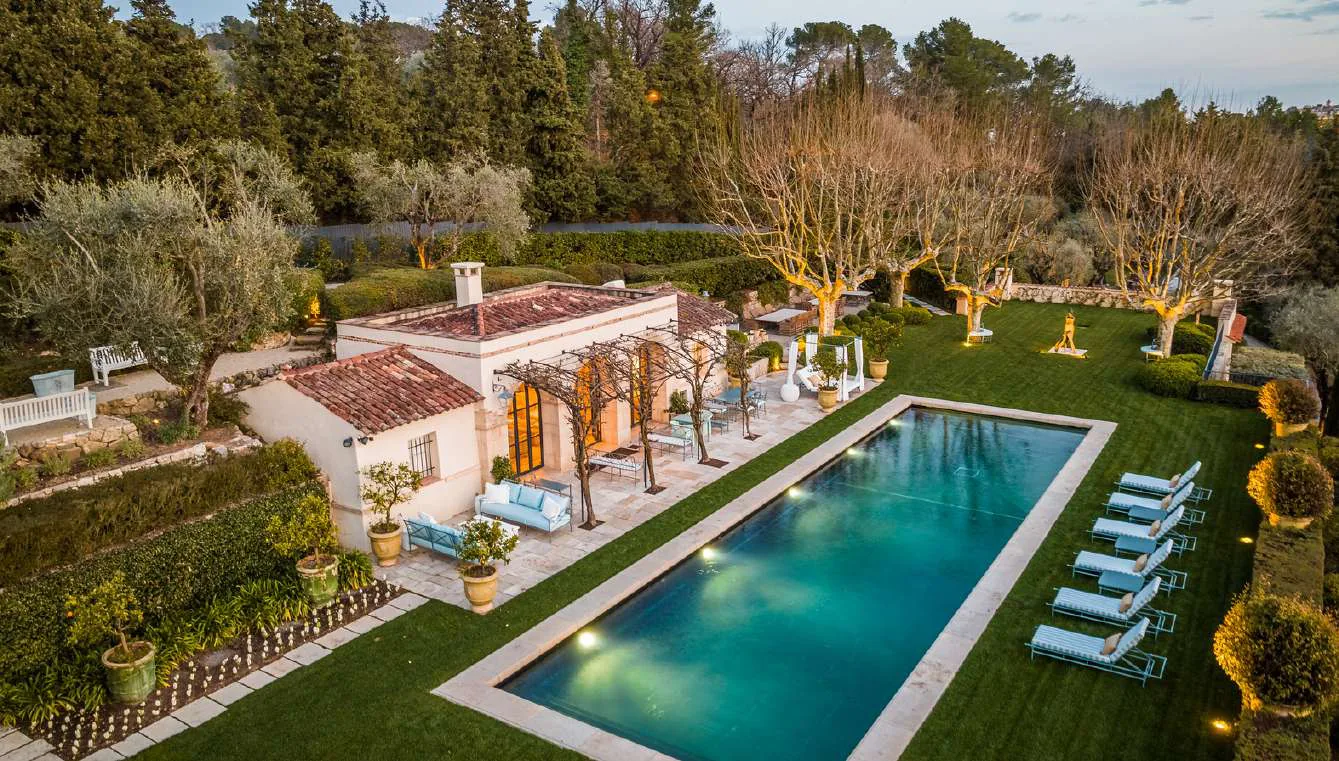 Piscine entouree de cypres avec bains de soleil au crepuscule