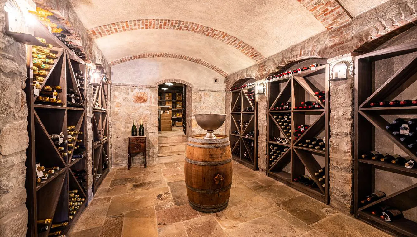 Cave a vins en pierre voutee avec casiers en bois et bouteilles vintage