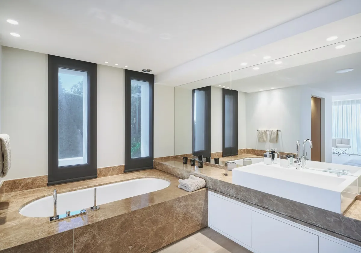 Salle de bain marbre brun avec baignoire ovale et fenêtres verticales