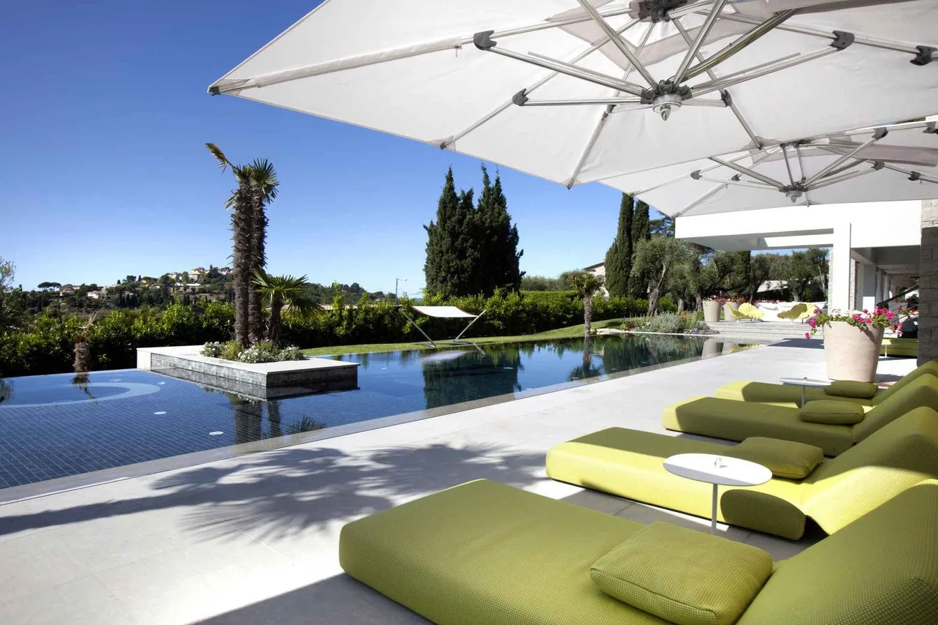 Terrasse piscine et bains de soleil verts sous parasols