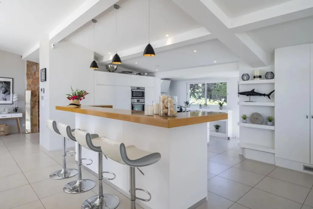 Cuisine en U avec bar haut tabourets crème et plan bois